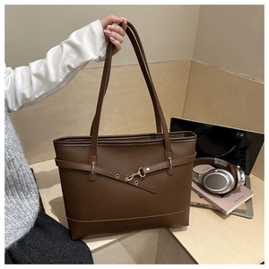 Detail of dark brown pebble leather tote bag with metal buckle and shoulder strap