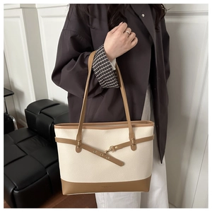 Detail of cream and brown tote bag showing lychee grain texture and gold buckle
