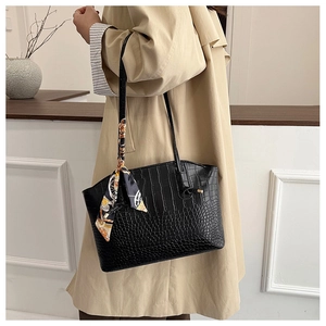 Detail of black faux leather tote with crocodile pattern and decorative silk scarf accessory