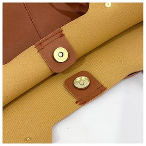 Detail of magnetic gold closures and fine stitching on a large leather tote bag interior