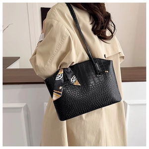 Detail of black crocodile texture tote bag with a geometric pattern silk scarf accent