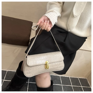 Detail of cream crocodile embossed handbag with golden clasp and long leather strap