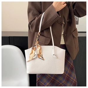 White crocodile embossed tote bag with floral silk scarf detail worn by a model
