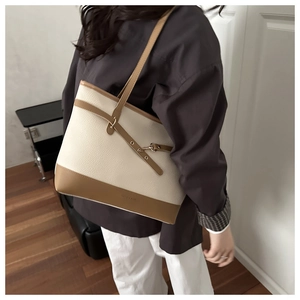 Close-up of litchi grain texture and gold metal buckle on contrast tote bag