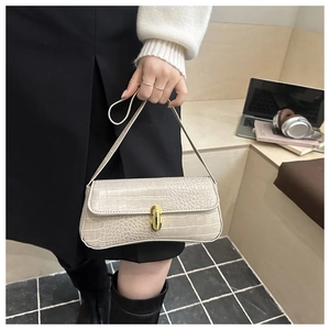 Detail of cream faux crocodile texture handbag with a golden cylinder clasp lock