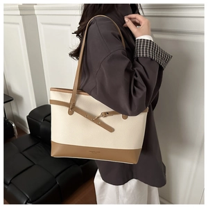Detail of large beige and brown leather tote bag with stylish gold buckles and metal eyelets