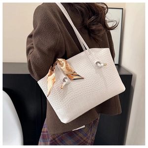 Detail view of white crocodile pattern tote bag with silk scarf on a model's shoulder