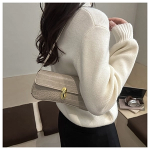 Detailed view of beige crocodile-embossed underarm bag with gold metal clasp