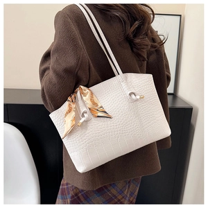 Close-up of white crocodile pattern tote bag featuring a decorative orange silk scarf
