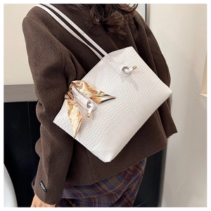 Macro detail of white faux crocodile texture tote bag with elegant silk scarf accessory