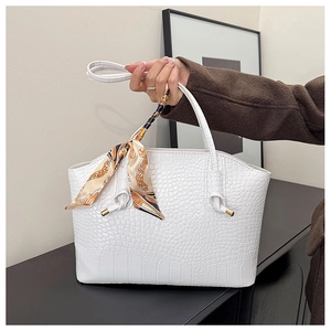 Detail of white crocodile embossed tote bag with elegant silk scarf on the handle