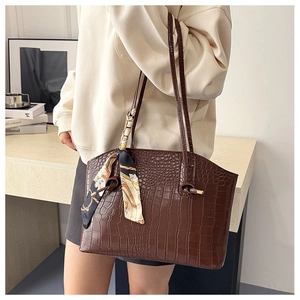 Detail view of brown crocodile pattern tote bag with decorative geometric silk scarf