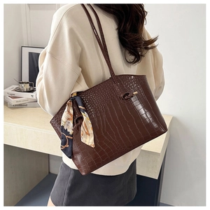 Brown crocodile texture tote bag with stylish silk scarf detail on a model's shoulder