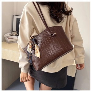 Brown crocodile pattern tote bag with decorative silk scarf on shoulder strap detail