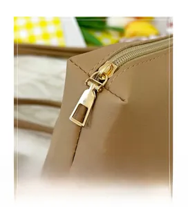 Detailaufnahme von goldenem Reißverschluss und präzisen Nähten an khakifarbener Tasche