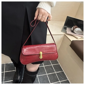 Detail of red crocodile texture leather handbag featuring a golden cylinder metal buckle