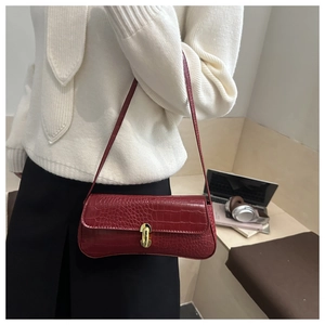 Detail of dark red crocodile embossed shoulder bag with golden metallic lock