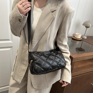 Minimalist black quilted crossbody bag with adjustable strap worn by model in casual style
