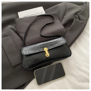 Close-up of black crocodile pattern faux leather baguette bag with gold metal buckle