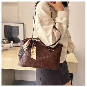 Detail of dark brown faux crocodile tote bag featuring a decorative silk scarf wrap handle