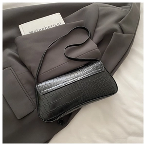 Detail of black faux crocodile pattern leather underarm bag with glossy vintage finish
