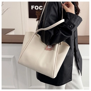Detail of creamy off-white leather tote bag with double straps worn by a model