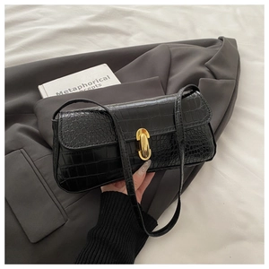 Detail of black crocodile pattern faux leather handbag with elegant gold metal buckle