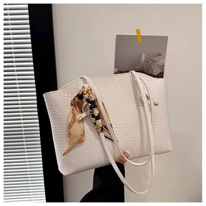 Close-up of white crocodile embossed tote bag with elegant silk scarf and gold chain detail
