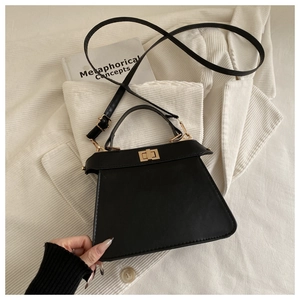 Top view of a black trapezoid crossbody bag with gold rotating lock and top handle