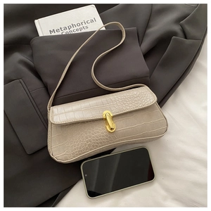 Detail of cream faux crocodile texture leather bag with gold buckle on grey blazer
