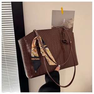 Detail of dark brown faux-crocodile tote bag featuring a silk scarf on the handle