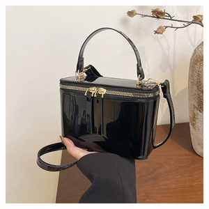 Detail of luxury black patent leather box bag with gold zipper and stylish handle