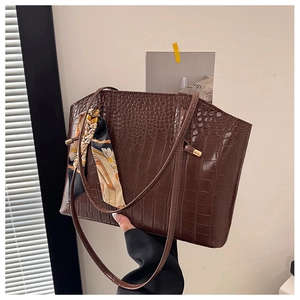 Close-up of brown crocodile texture tote bag featuring a stylish decorative silk scarf