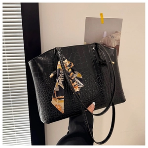 Detail of black crocodile texture tote bag with elegant printed silk scarf on handle