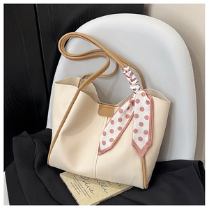 Detail of cream tote bag with brown handles and a pink polka dot silk scarf wrap