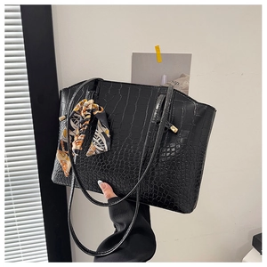 Detail of black faux crocodile leather tote bag with elegant silk scarf on handle