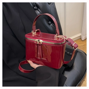 Detailed view of glossy burgundy patent leather vanity case bag with gold hardware