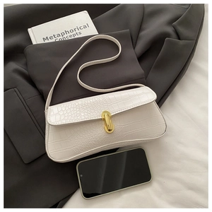 Close-up of white crocodile pattern shoulder bag with a gold oval metal clasp