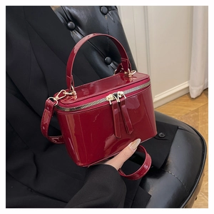 Macro detail of red patent leather mini box bag with gold-tone hardware and zippers