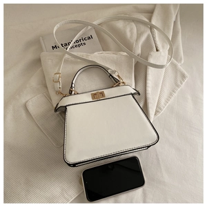 Top view of a white trapezoid leather handbag with gold twist lock on corduroy fabrics