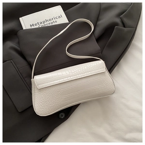 Detail of white crocodile pattern baguette bag on grey blazer with minimalist aesthetic