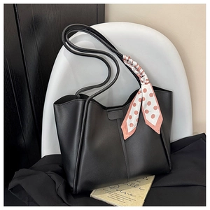 Detail of black leather tote bag featuring slim straps and decorative polka dot silk scarf