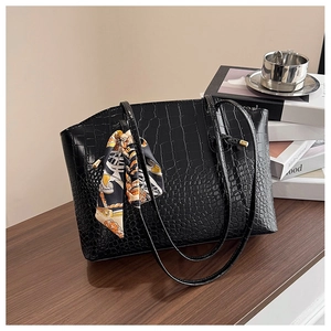 Detail of black faux leather tote with crocodile texture and silk scarf decoration