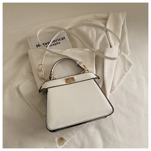 Detail of white trapezoid handbag with gold metal twist lock and smooth leather texture