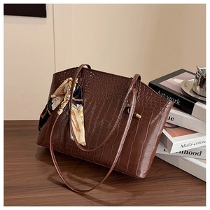 Detail of dark brown faux crocodile embossed tote bag with elegant floral scarf accessory