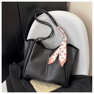 Detail of black leather tote bag featuring a pink polka dot scarf on handle