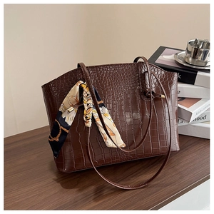 Close-up of dark brown crocodile pattern tote bag with vintage chain print scarf