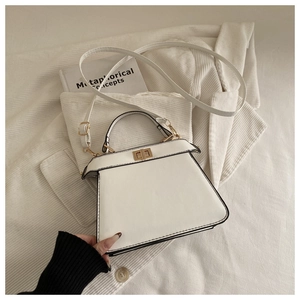 Detail of white leather trapezoid handbag with gold rotating lock and long shoulder strap
