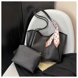 Black leather tote bag and clutch set with polka dot scarf detail on a white chair