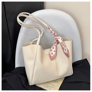 Detail of cream white leather tote bag with polka dot scarf on a minimalist chair